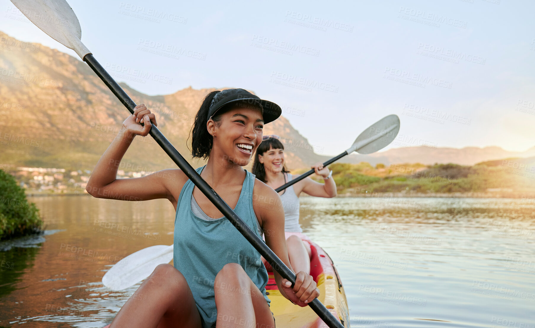 Buy stock photo Two smiling friends kayaking on a lake together during summer break. Smiling and happy playful women bonding outside in nature with water activity. Having fun on a kayak during weekend recreation