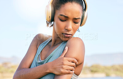 Buy stock photo Young african american sportswoman suffering from shoulder pain while training. Woman holding her shoulder in pain while exercising outside. Overworking can lead to injury
