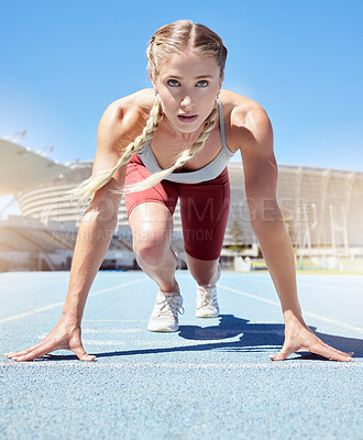 Determined female track runner in starting position. Front view of fit active sportswoman mentally and physically prepared to start sprinting running. Athlete exercising for cardio health and stamina