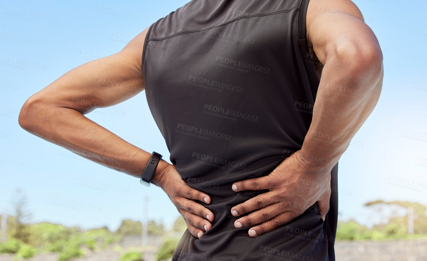 Buy stock photo Rearview of athlete with back pain. Closeup back view of an uncomfortable young sportsman standing on a sport field holding his stiff and inflamed joints. Muscle or spinal strain due to injury