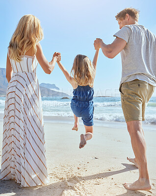Buy stock photo Family enjoying a fun day at the beach, and playing with their little girl. Rear view of a blonde mother and father swinging their cute little daughter in the air at the beach on a sunny summer day