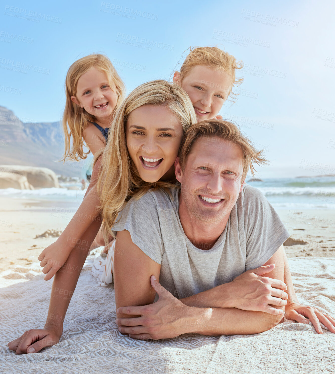 Buy stock photo Portrait of a carefree family relaxing and bonding on the beach. Two cheerful little girls having fun with their parents on holiday. Mom and two daughters lying on top of dad enjoying vacation