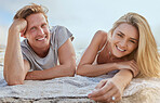 Portrait of happy young couple lying on blanket and enjoying beach vacation. Smiling young blonde man and woman lying on shore and enjoying their honeymoon or romantic date on a summers day