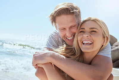 Buy stock photo A young loving couple enjoying a day at the beach while smiling hugging and having fun, showing affection at the ocean. Romantic couple cuddling and laughing with joy while on summer vacation
