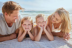 Portrait of a carefree family relaxing and bonding on the beach. Two cheerful little girls spending time with their mother and father on holiday. Mom and dad admiring their daughters on vacation