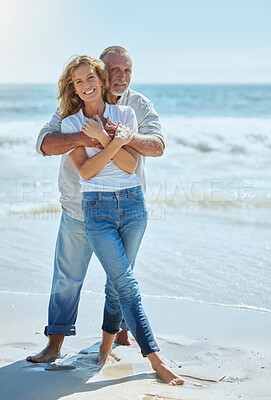 Buy stock photo Portrait of a happy and loving mature couple enjoying a day at the beach in summer. Cheerful affectionate senior husband hugging his joyful wife while standing in the water on holiday