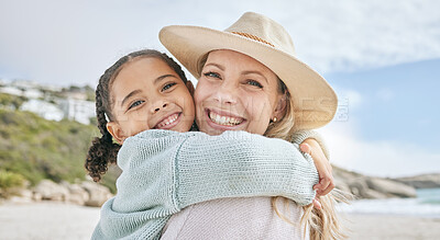 Buy stock photo Portrait of a little girl bonding and hugging her mother at the beach. Carefree mom having fun with her adopted little kid for a summer vacation by the sea. Loving mother and daughter relationship