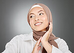 Beautiful muslim woman posing in a studio wearing a hijab. Headshot of a happy and confident arab model standing against a grey background. Fashionable woman wearing a headscarf

