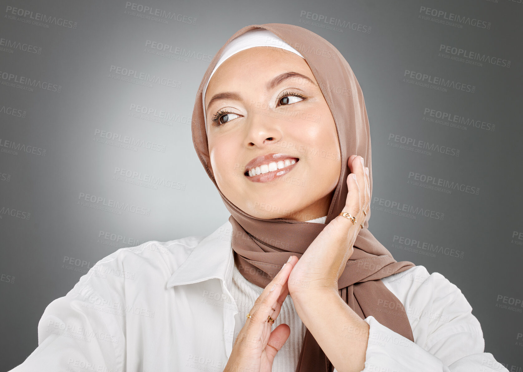 Buy stock photo Beautiful muslim woman posing in a studio wearing a hijab. Headshot of a happy and confident arab model standing against a grey background. Fashionable woman wearing a headscarf

