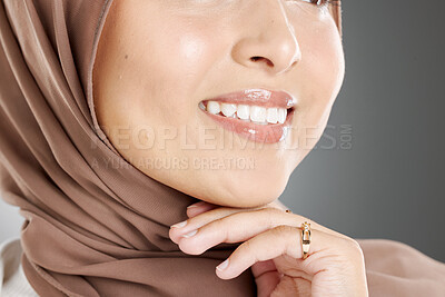 Buy stock photo Young woman wearing a hijab or headscarf showing her natural looking veneers after getting a dental treatment. Closeup of a muslim woman's face and teeth isolated against a grey background.