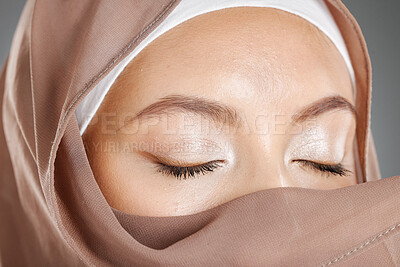 Buy stock photo Closeup of a beautiful Muslim woman covering her beauty with her scarf and showing shimmery eyeshadow. Face of a stunning muslimah closing her eyes and showing perfect eye makeup look with a hijab