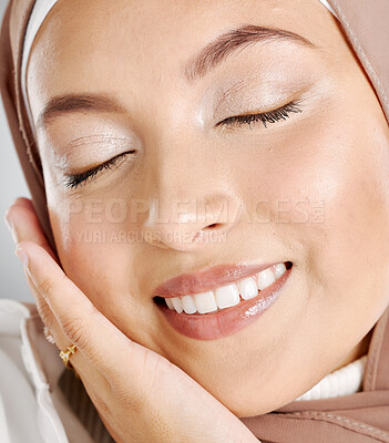Closeup of beautiful muslim woman with eyes shut satisfied with her skincare regime. Headshot of a stunning arab model with natural makeup touching her face. Face of glowing middle eastern woman