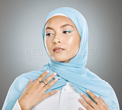 Buy stock photo A glowing beautiful muslim woman isolated against grey copyspace background. Young woman wearing a hijab or headscarf showing her eyelash extensions while daydreaming, touching her flawless skin 