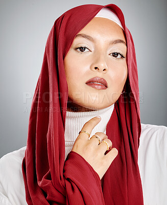 Buy stock photo Portrait of a Muslim woman wearing a red hijab or headscarf showing her eyelash extensions and makeup. Showing her flawless skin glowing. Beautiful woman isolated against a grey studio background. 