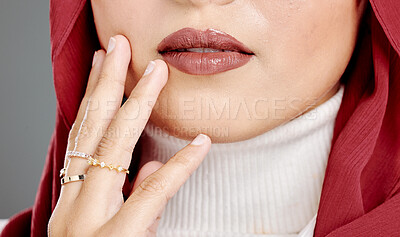 Closeup of unknown muslim woman touching her face, wearing a hijab and posing in studio. Half headshot of confident arab model isolated against grey background. Zoomed in on fashionable middle eastern