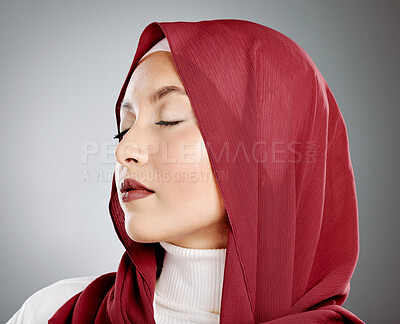 Pretty young muslim woman in hijab with her eyes closed on a grey background studio. Middle eastern woman of islam religion wearing a headscarf