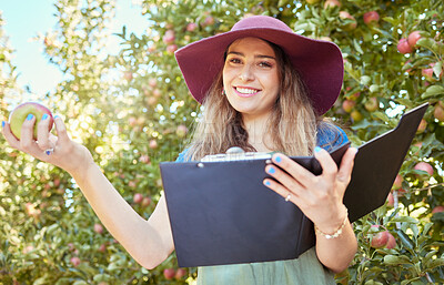 Buy stock photo Woman holding an apple and a clipboard on a sustainable orchard farm in summer. Happy farmer doing stock taking and checking a checklist while harvesting fresh organic green and red fruit from trees