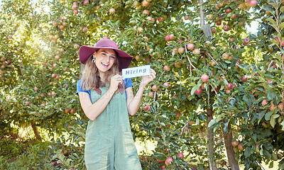 Female apple farmer hiring workers to help on her fruit farm during harvest. Portrait of happy young woman advertising in an orchard on a sunny day near trees. Fresh produce growing in agriculture