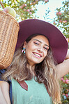 Portrait of one happy woman holding basket of fresh picked apples from trees on sustainable orchard farm outside on sunny day. Face of cheerful farmer harvesting juicy organic fruit in season to eat