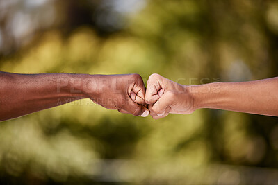 Buy stock photo Fist bump of two interracial men outdoor against a blur background. Closeup of diverse athletes doing social gesture greeting in a park. Showing solidarity, friendship, brotherhood, teamwork or unity