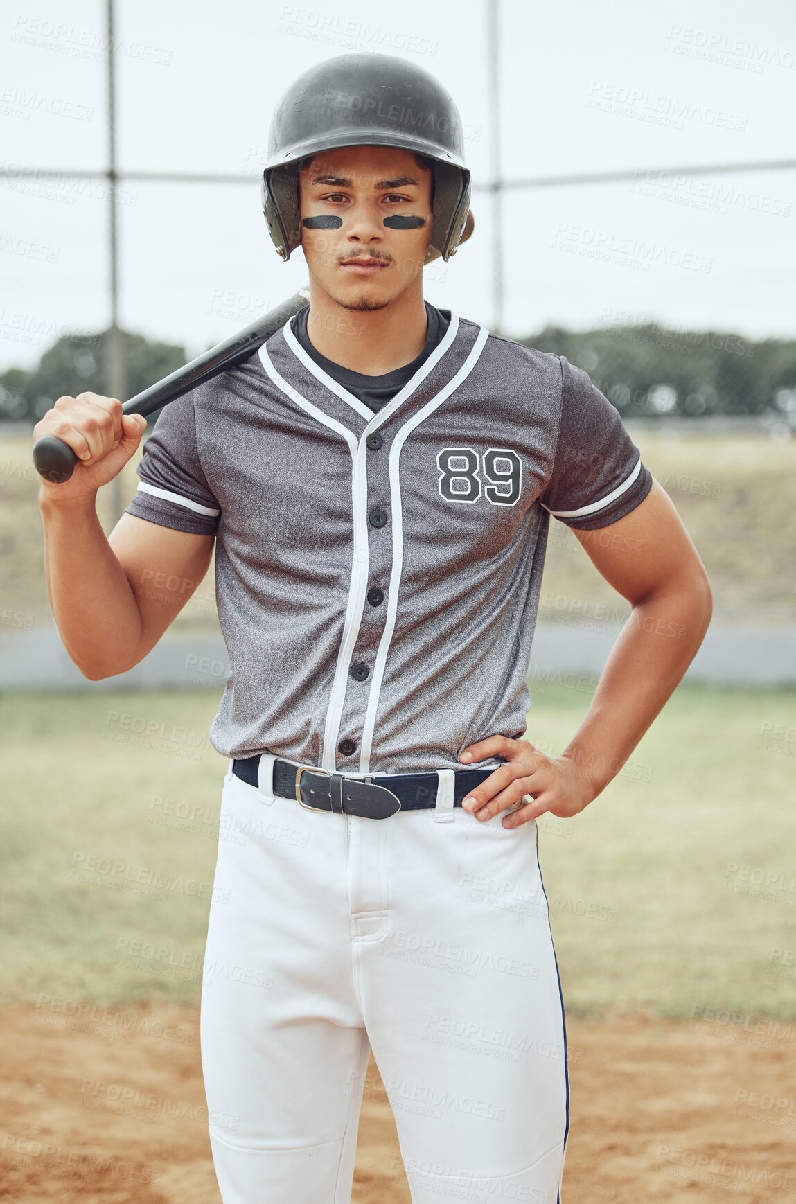 Buy stock photo Portrait of baseball player looking focused with paint on his face. Serious and fit, active athlete wearing a helmet during a game on a pitch. Sporty man holding a bat before playing a match