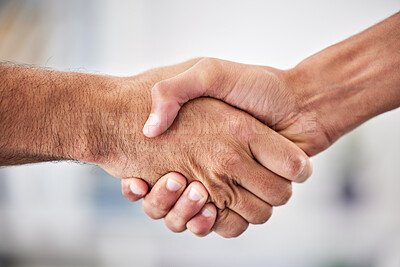 Closeup of two businessmen shaking hands in the office. Unknown mixed race professionals and colleagues sealing a deal with a hand gesture. Mixed race manager welcoming, promoting a business partner