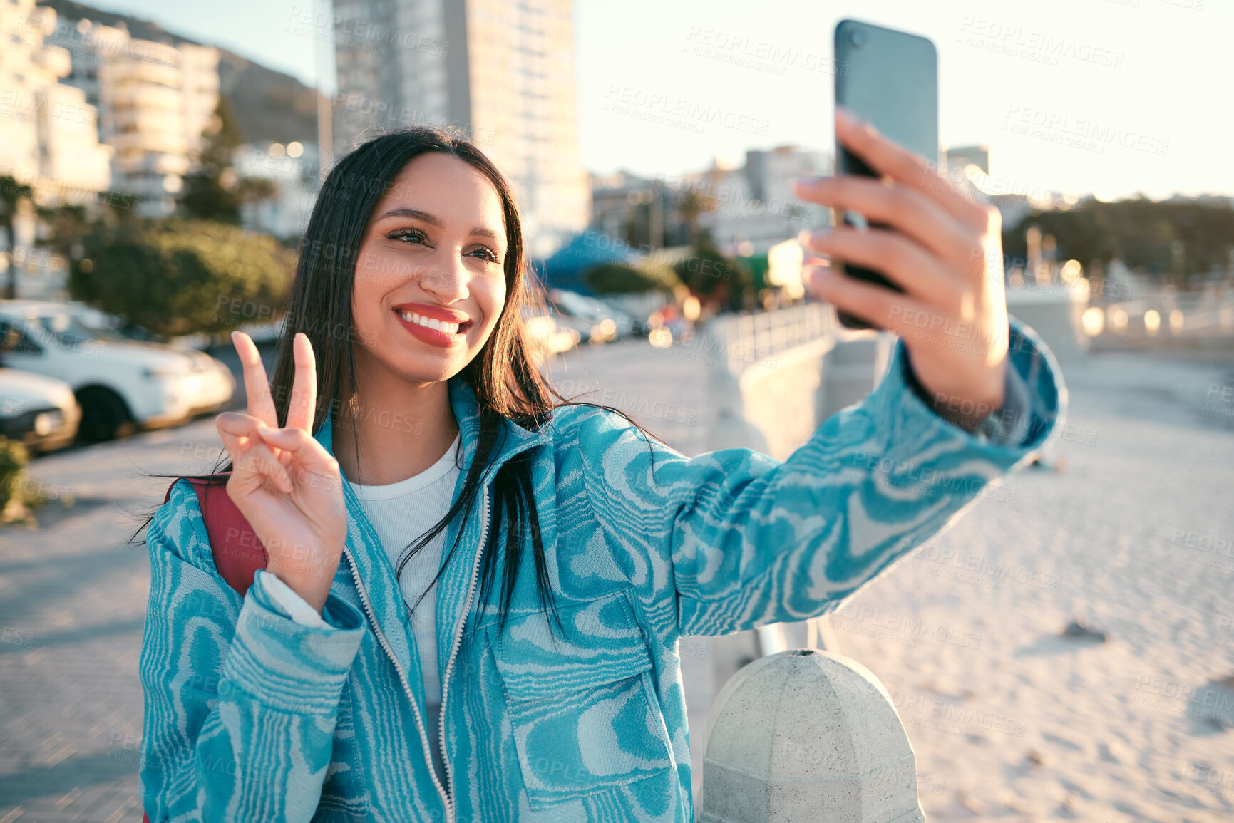 Buy stock photo Fun, happy and trendy student taking a selfie on phone for social media while exploring, visiting or enjoying city. Stylish, edgy and funky woman showing peace sign, symbol and gesture for social app