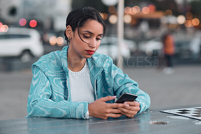 Sad, depressed and stressed female with mental health problem texting on phone while sitting at outdoor cafe. Young woman getting negative response or bad news while chatting or browsing social media