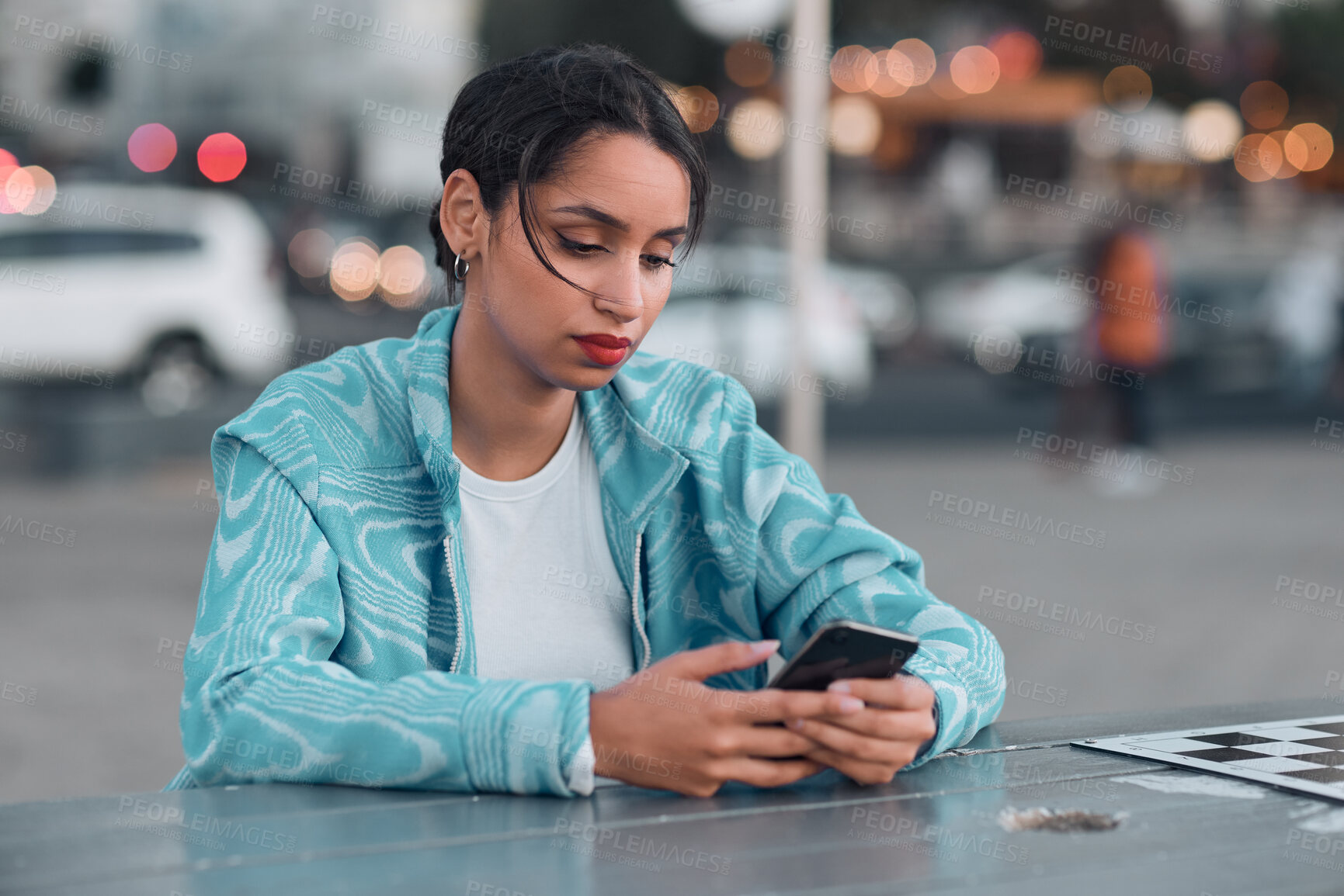 Buy stock photo Sad, depressed and stressed female with mental health problem texting on phone while sitting at outdoor cafe. Young woman getting negative response or bad news while chatting or browsing social media