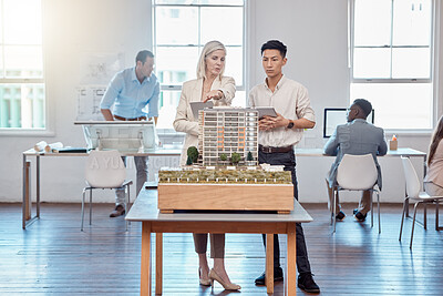 Buy stock photo Confident business professionals in the field of architecture working together on building designs in a modern office. Team of male and female architects talk over a model construction for a project.