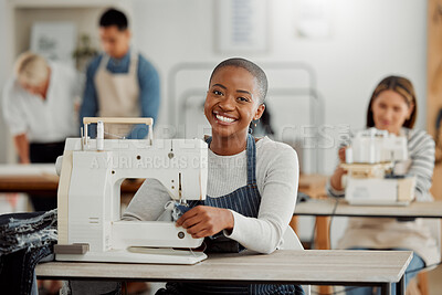 Portrait of happy black fashion designer working on new clothes in workshop. Diverse group of students doing an internship at a clothing factory, learning about the industry and how to sew on machine