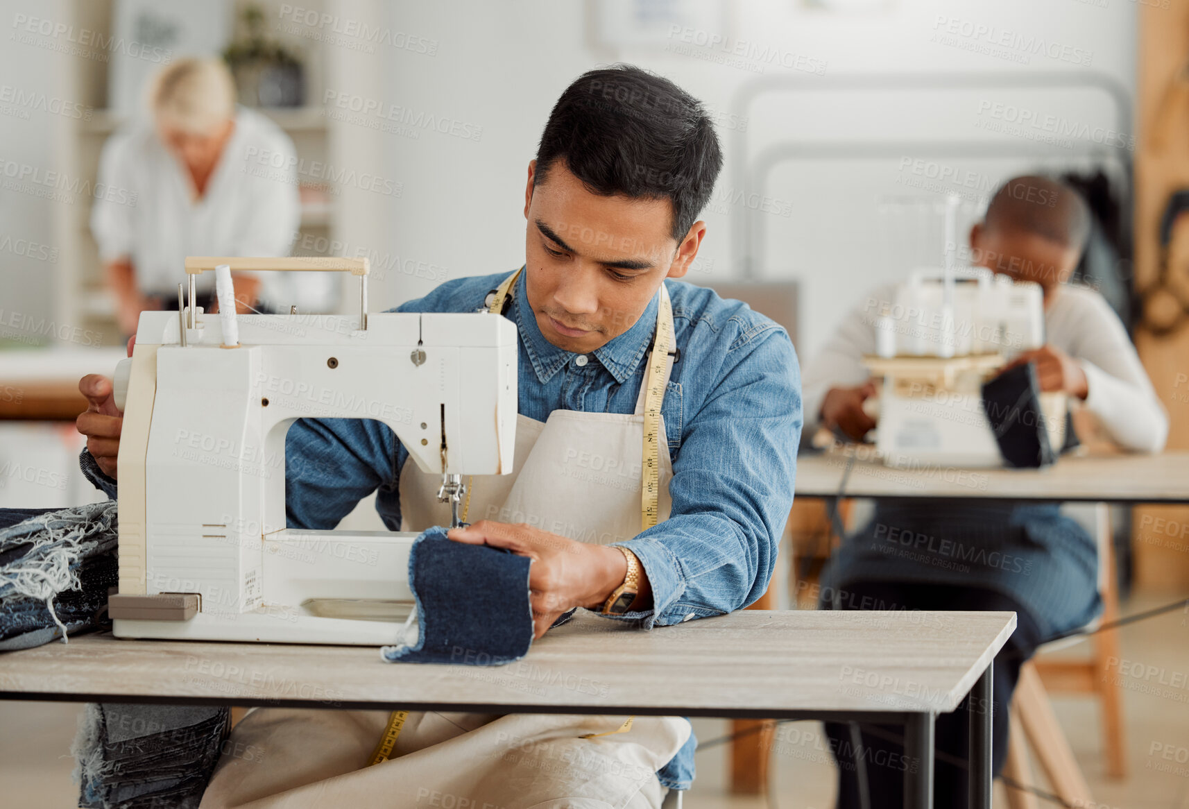 Buy stock photo Creative fashion designer learning sewing skills on denim clothes in a clothing manufacturing factory. Young and fashionable student using a sewing machine in a workshop working with stylish fabric
