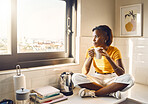 Thinking, serious and African woman drinking coffee while sitting on the kitchen counter alone at home. One content, carefree and peaceful black female enjoying a cup of tea while looking thoughtful