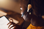 Young student browsing, scrolling and searching the web at night on a tablet. Woman watching education videos with headset, learning from a correspondence course and participating in an online class