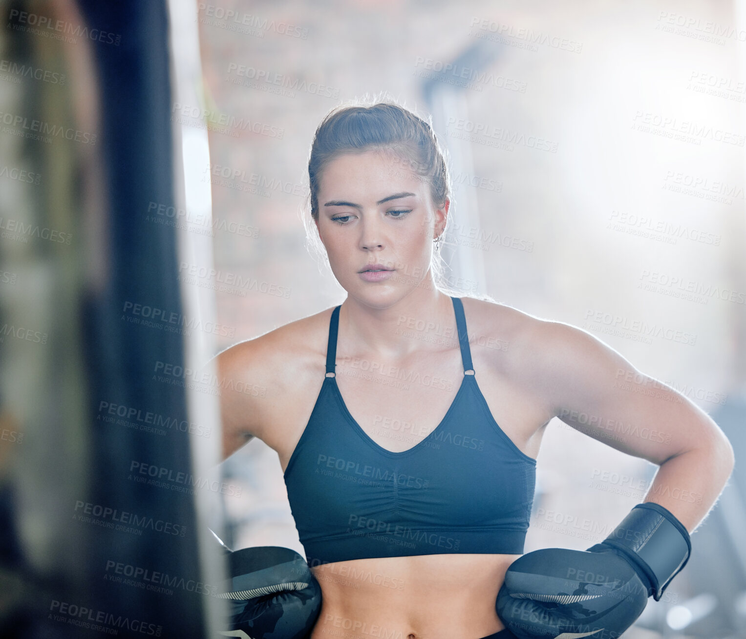 Buy stock photo Healthy, fit and active female boxer thinking about a fight, competition or match in the gym or health club. Young woman training, exercising and working out in a fitness studio and looking dedicated