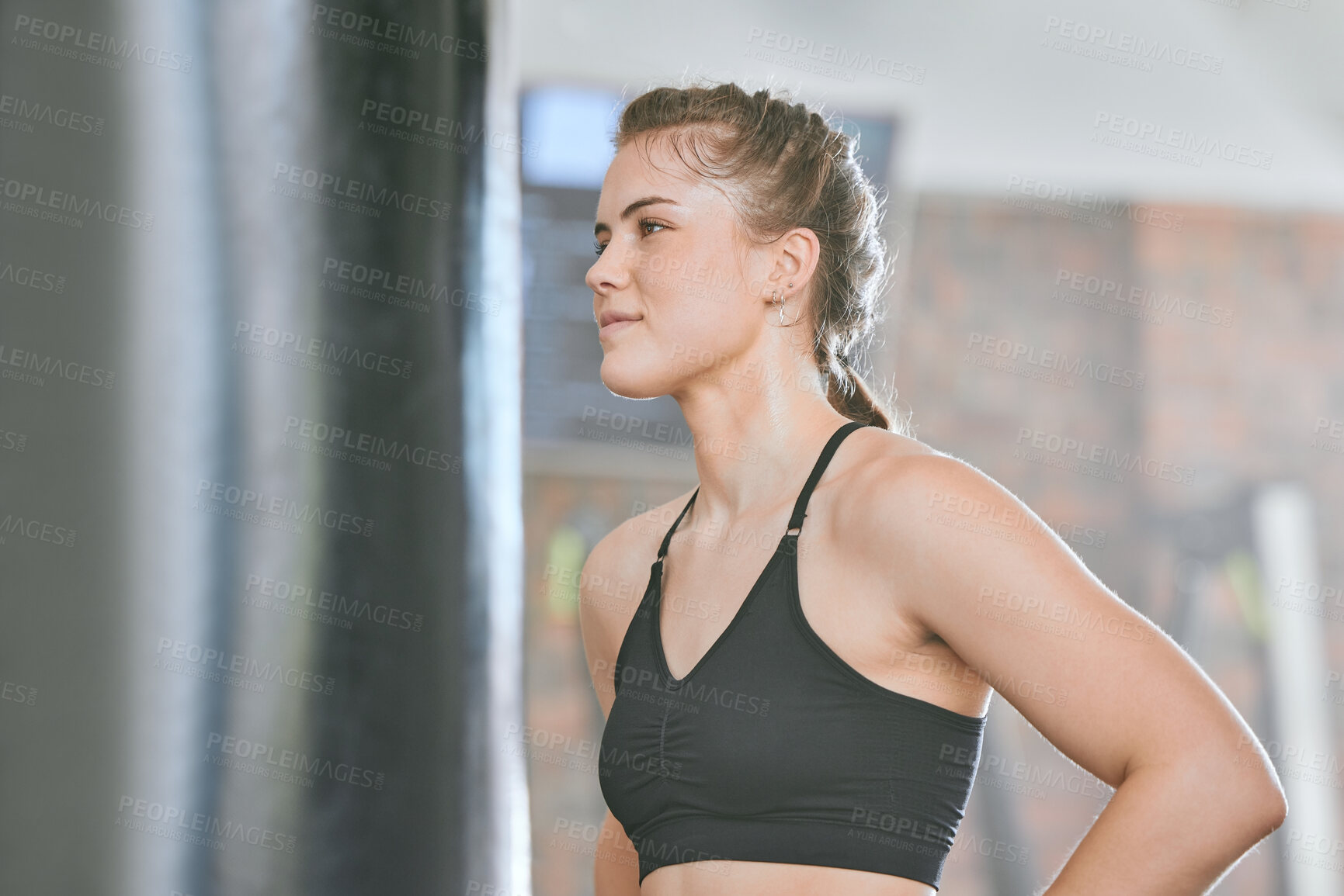 Buy stock photo Healthy, fit and active female boxer thinking about a fight, competition or match in the gym or health club. Young woman training, exercising and working out in a fitness studio and looking dedicated