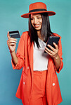 Happy and excited female online shopping, buying with a credit card or paying bills on a phone. Isolated cheerful lady making a purchase on a website, standing in front of blue copyspace background.