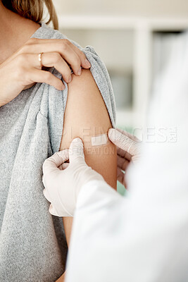 Buy stock photo Covid, vaccine and injection with a doctor placing a plaster on the arm of a female patient in the hospital after a booster shot. Closeup of cure and treatment during the corona virus pandemic