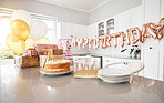 Birthday, kitchen and cake stand with balloons for house party. Happy event, gifts and baked sweet goods for guests to eat. Decorations, special celebration and beautiful table of presents