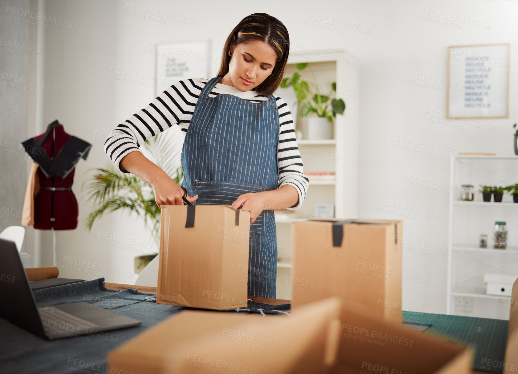 Buy stock photo Creative designer packing order in box, tailor organizing package for courier delivery service and closing product parcel working at design studio, boutique or shop. Business owner unpacking supplies