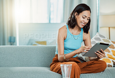 Buy stock photo Streaming movies to watch online on digital tablet, watching videos and scrolling on social media while relaxing on the couch alone at home. Happy, smiling and casual female browsing the internet