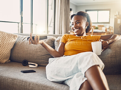 Buy stock photo Relaxed, carefree and smiling young female watching tv and streaming movie at home on her living room sofa. Happy, casual and comfortable woman sitting on her couch and enjoying her leisure free time