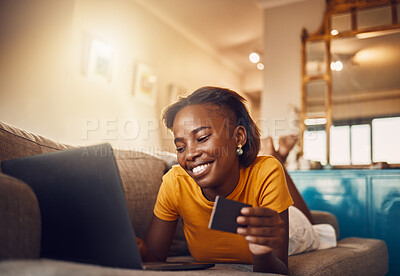 Buy stock photo Online shopping young, happy and smiling African lady with bank, credit or gift card. Excited, comfortable and cheerful ethnic female typing on laptop searching, browsing and buying present from home