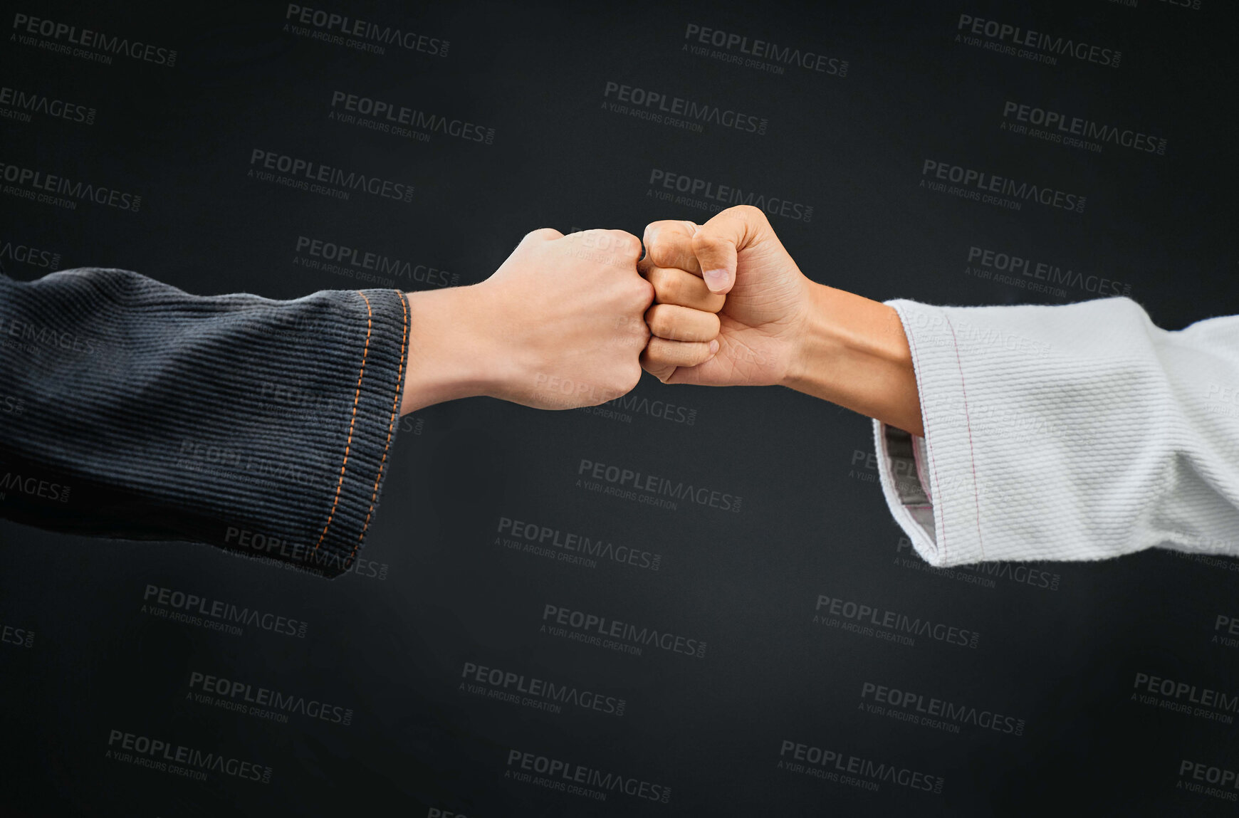 Buy stock photo Teamwork, respect and discipline with hands fist bumping before a fight, match or mma competition. Closeup of two athletes greeting before combat sport and self defense against a black background