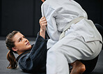 Strong, female and martial arts fighter training at an exercise studio with an opponent. Fit, young and active woman in a defense lesson at a dojo. Athlete lady practicing jujutsu with a partner.