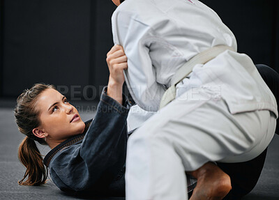Buy stock photo Strong, female and martial arts fighter training at an exercise studio with an opponent. Fit, young and active woman in a defense lesson at a dojo. Athlete lady practicing jujutsu with a partner.