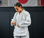 Mma, karate and self defense with a young woman getting ready in her gi or uniform for training, exercise and practice. Workout, sport and fighting with a female athlete standing in a gym or studio