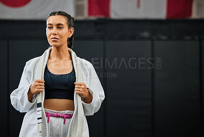 Buy stock photo Mma, training and martial arts with a sporty young female fighter getting ready for a fit, match or competition in her gi or uniform. Training, exercise and sparring with a woman standing in a gym