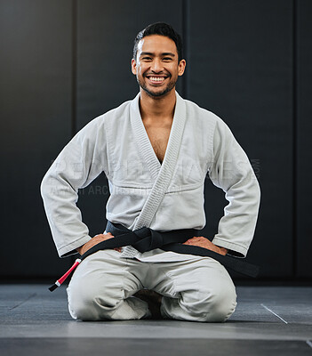 Buy stock photo Mma, karate and training with a young man kneeling in a gym, health studio or dojo in his gi or uniform. Portrait of a male training, exercising and learning self defense in a workout and fight class