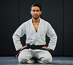 Male coach ready for karate training at fitness studio, looking serious at dojo practice in gym and sitting on the floor at a self defense class. Portrait of tough, healthy and active trainer